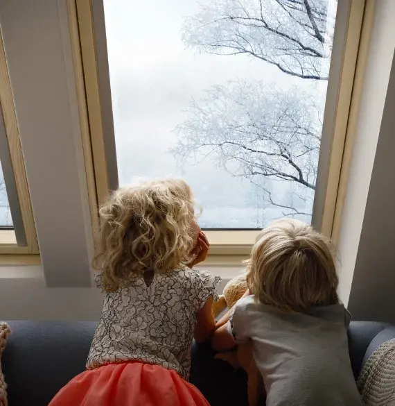 dzieci wyglądające przez drewniane okna dachowe
