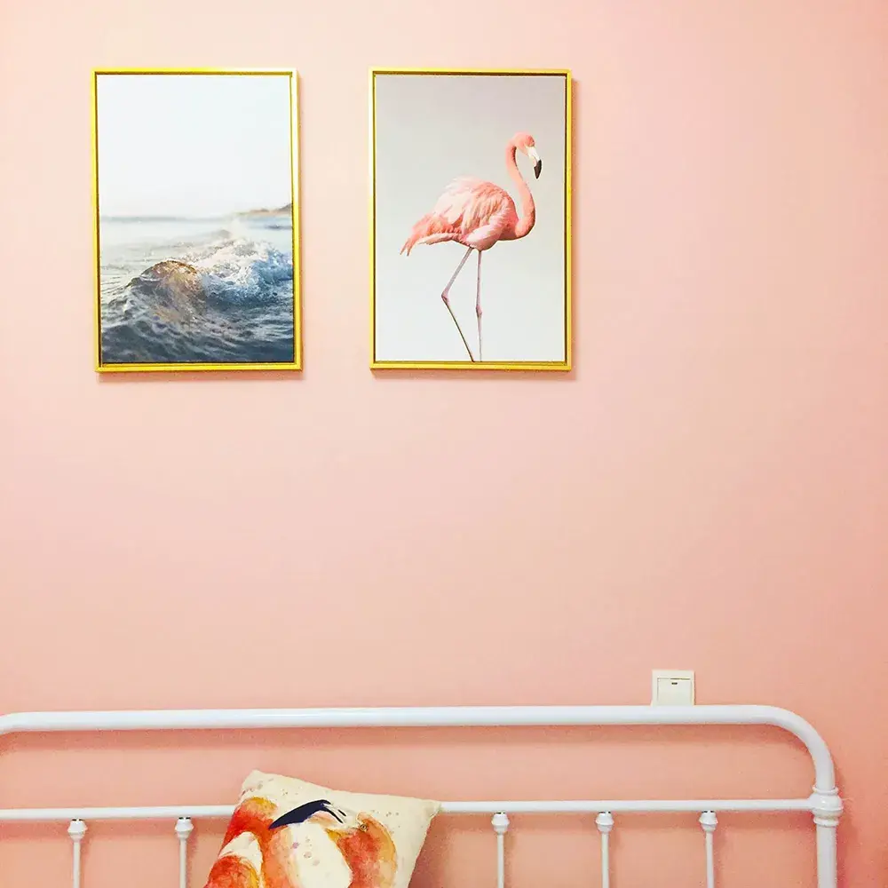 różowa ściana dwa obrazki i zagłówek łóżka